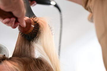 Stylist using a hair brush and a hair dryer in a bright modern salon