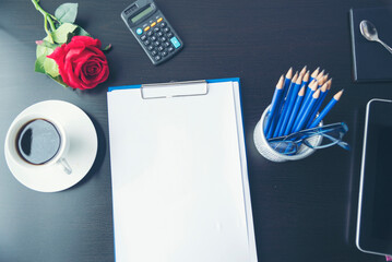 Top view office desk smart tablet document paper, coffee cup roses on wood table with copy space. Tabletop notebook office empty blank white paper pen coffee cup to display workspace wood background