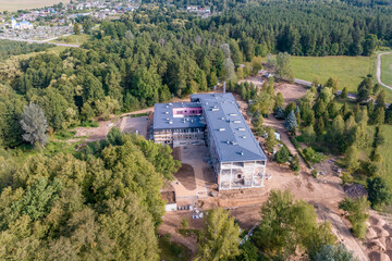 construction of a multi-storey building, hotel or sanatorium clinic in the middle of a forest from a bird's eye view - obrazy, fototapety, plakaty