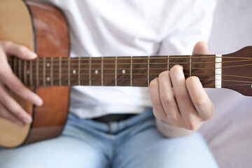 Young man playing acoustic guitar, closeup. Music education concept.