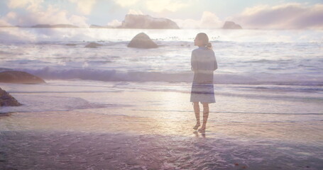 Fototapeta na wymiar Rear view of a woman walking on the beach barefoot on a sunset