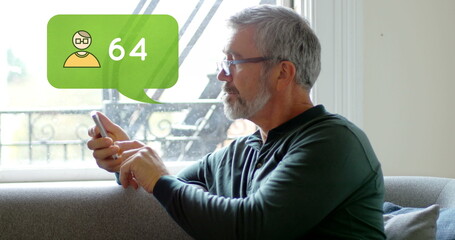 Side view of an old man seated on a couch while typing on his phone