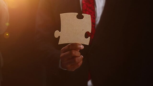 See the big picture. Close-up of an unidentified business man holding two puzzle pieces together.