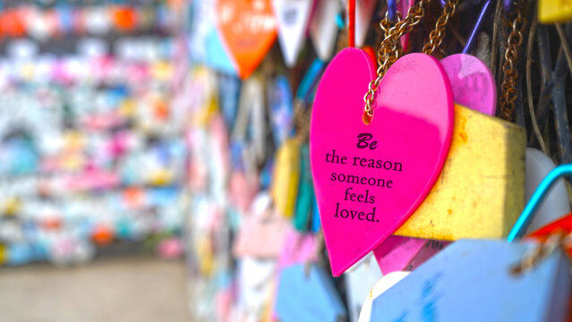 Colorful hearts on street with text message on pink color - Be the reason someone feels loved. Kindness and humanity concept.