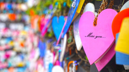 Colorful hearts on the street hanging on wall with random love text messages - Miss you.
