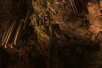 Interior de una cueva con estalactitas colgando del techo.
