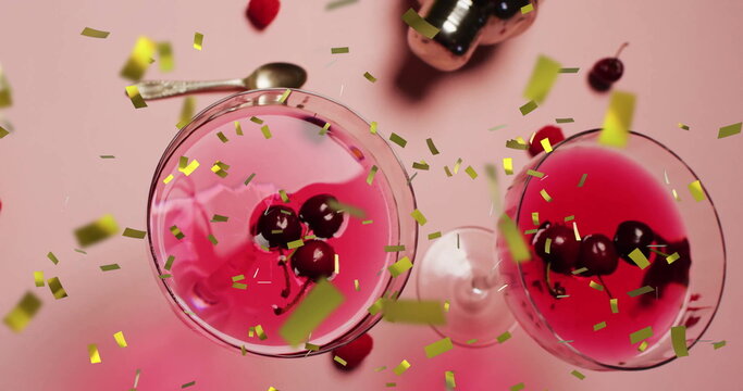 Image of confetti falling and cocktail on pink background