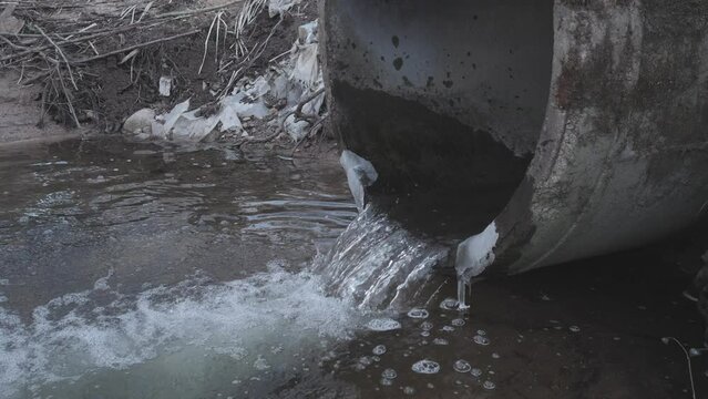 Dirty water flows from the pipe into the river, environmental pollution