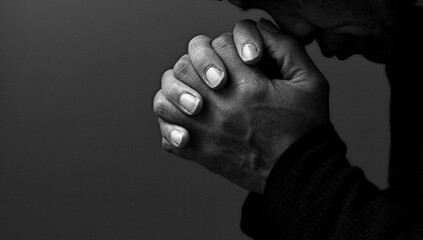 black man praying to god with hands together Caribbean man praying on black background with people...
