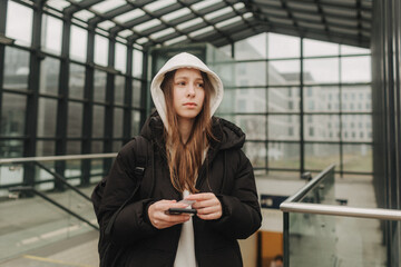 Tourist teenage girl at train station using smartphone map, social media check-in, or buy ticket booking. Modern travel app technology, lone traveler, Winter vacation railroad adventure concept - 757022225