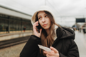 Tourist teenage girl at train station using smartphone map, social media check-in, or buy ticket booking. Modern travel app technology, lone traveler, Winter vacation railroad adventure concept - 757022685