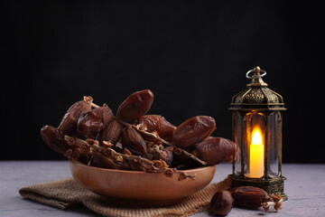 pile of dates fruit in bowl with antique candle lantern and isolated black background