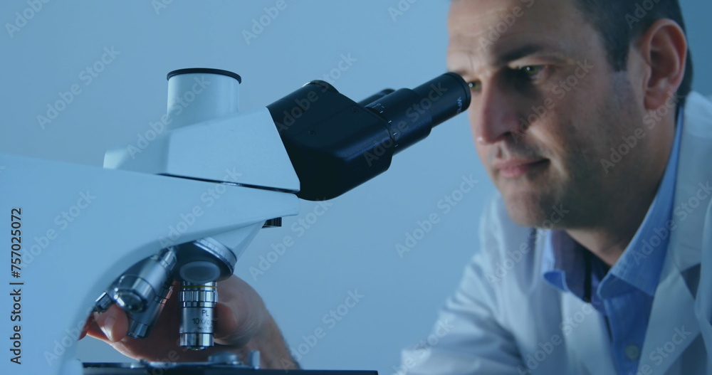 Poster caucasian scientist examines samples under a microscope in a lab