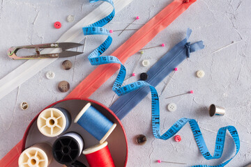 Measure tape, needles, colored threads, pins, and buttons for fashioned clothes production fabric...