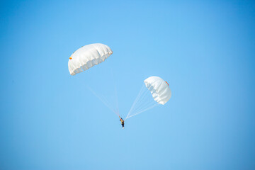 Skydiving. Flying parachutists against the background of the blue sky and mountains. Extreme sport and entertainment.