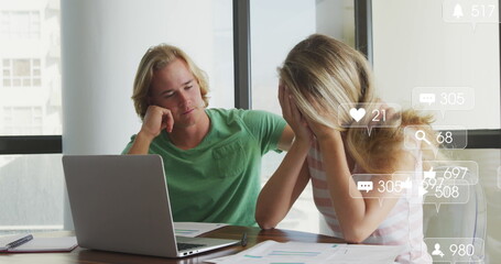 Multiple digital icons with increasing numbers over stressed caucasian couple calculating finances