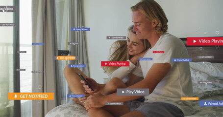 Multiple digital icons over caucasian couple using smartphone together in the bed at home