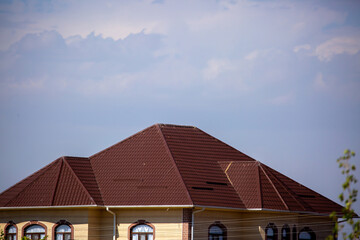 Roofs of houses from a metal profile against the sky. Roofing. Metal tiles on the roofs of houses.