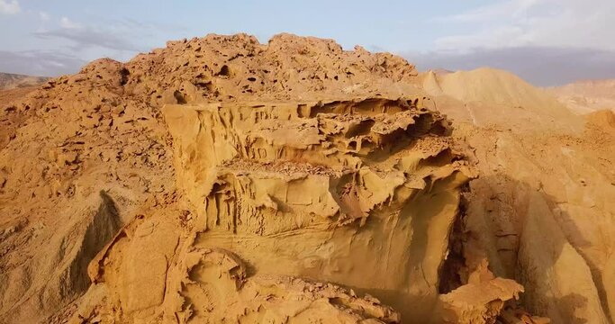 Fly back from wind erosion rock cliff landform the coastal marine sea side cliff golden color in sunset time near the ocean beach in middle east Asia Qatar UAE border the gulf water adventure trip