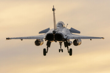 Avión de combate aterrizando al ocaso