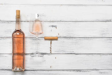 Rose wine in a bottle, in a glass and a corkscrew on a white wooden table. Top view, flat lay. Wine tasting concept. Pink wine. - 757039094