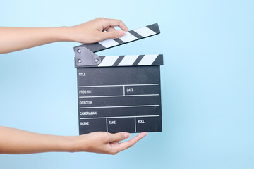 Hands holding movie clapper on blue background