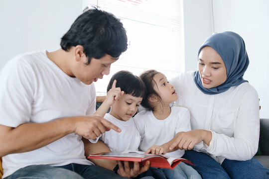 Happy Asian Family Spending Time Together Reading Book at Home 