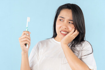 A person grimacing in pain as they brush their teeth. Close-up of a person's mouth with a...