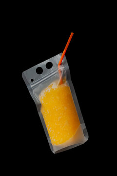 Orange Slush or Granizado in leak-proof plastic drink pouch on dark background. Refreshing summer drink. Fruits iced slushie or Sweet citrus shaved ice. Convenient package take away