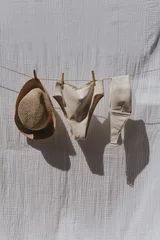 Foto op Aluminium Female swimwear and straw hat hanging over white cotton cloth with strong shadows. Sunbathing on a summer sunny day concept © Floral Deco