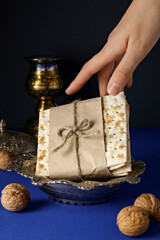 Matzo in hand, nuts and cup on dark blue background