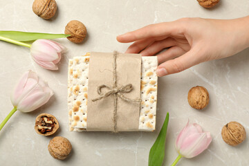 Matzo, hand, flowers and nuts on beige background, top view