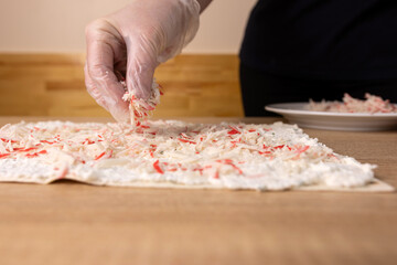 Crab sticks are added to the unfolded pita bread. Preparation of pita bread roll.