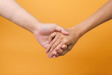 Portrait of man and woman hand holding each other over yellow background