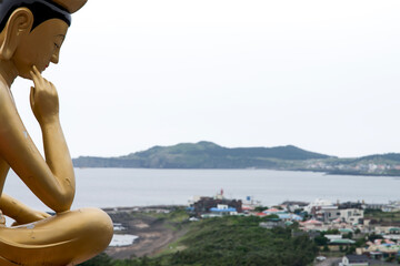 Fototapeta na wymiar View of the Buddha statue looking at the fishing village