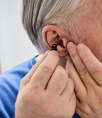 Hearing aid in the ear of elderly man, close-up. ITC hearing aid for hear treatment