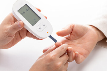 close up doctor measuring glucose by glucometer on white.