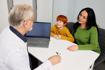 Friendly pediatrician meeting with male child and his mother in medical clinic while consultation. Children's healthcare