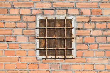 Abandoned warehouse window. Rusty grate window. Safety security protection. Red brick wall with metal grate window cover. Basement background.