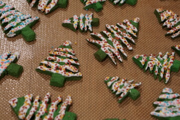 Top view of Christmas tree-shaped cookies with sugar coating, resting on a silicone baking mat.