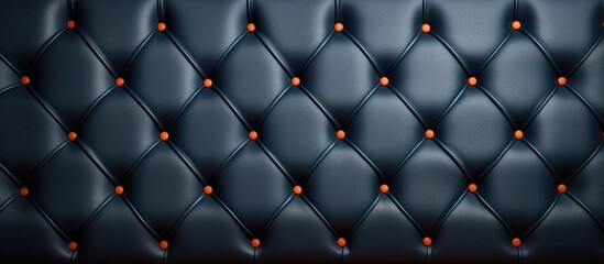 A detailed shot of a black leather couch featuring orange buttons, resembling the pattern of an automotive tire with a touch of electric blue