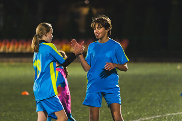 medium shot of young soccer players shaking hands and congratulating win, children sports concept....