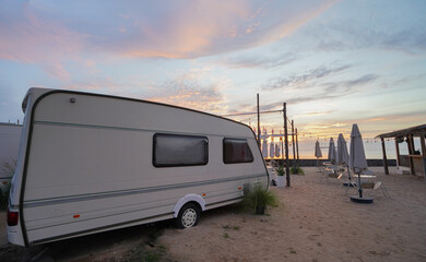 The motorhome is camped out on the sandy beach by the sea in the morning.