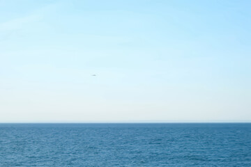 Airplane plane flying over the sea in clear blue sky at sunny weather. Passenger jet approaching to...