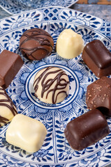 Variety of luxury belgian chocolate pralines bonbons on blue china porcelain plate, tea time