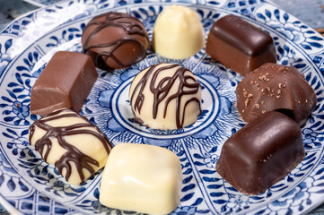 Variety of luxury belgian chocolate pralines bonbons on blue china porcelain plate, tea time
