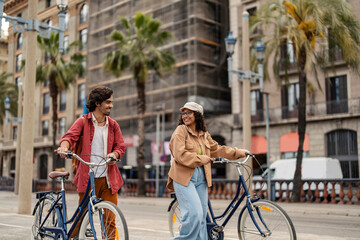 Happy couple is enjoying walk on a street and pushing their bicycles.