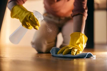Fotobehang Lengtemeter Cropped picture of a woman kneeling and cleaning floor with spray and rag.
