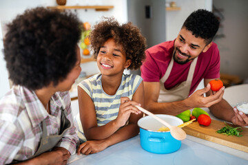 Happy african american parents and child having fun preparing healthy food in kitchen