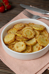 Slices of fried crookneck in oil with garlic on a wooden background